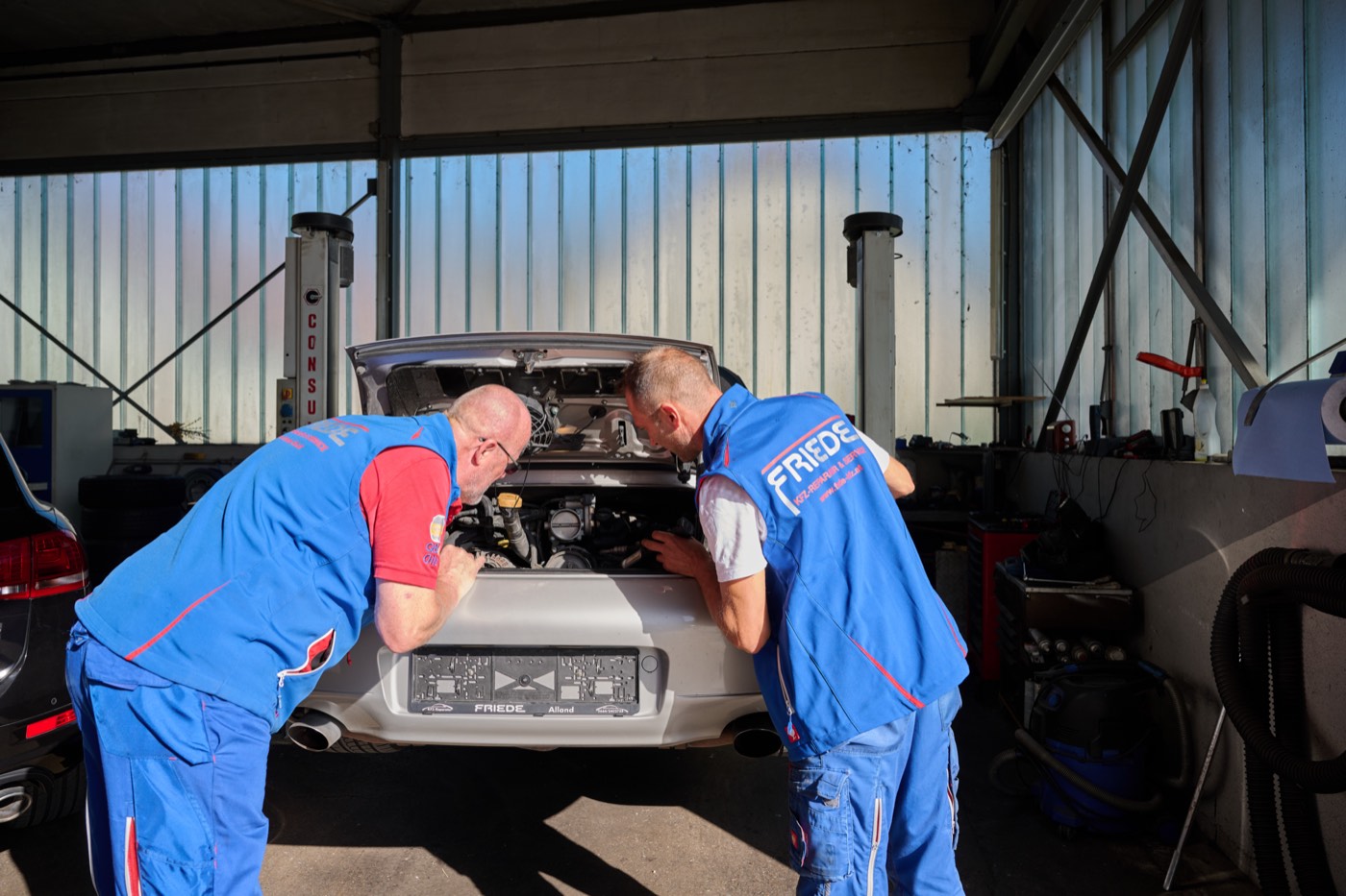 Zwei Mechaniker arbeiten gemeinsam am Motorraum eines Autos