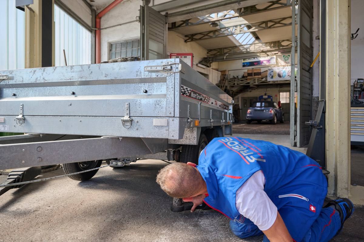 Mechaniker prüft die Unterseite eines Anhängers
