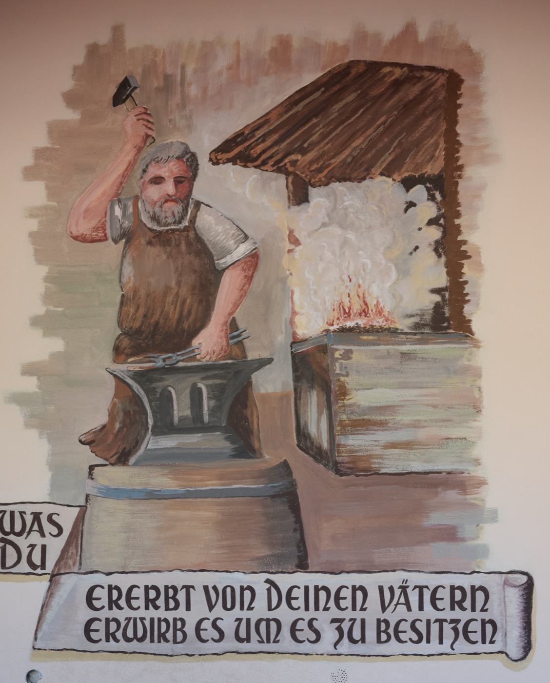 Wandbild: ein Schmied am Amboss, darunter der Spruch „Was du ererbt von deinen Vätern, erwirb es, um es zu besitzen“